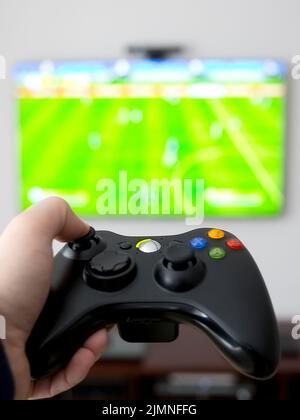 TV su una parete grigia e premere a mano il game pad Foto Stock