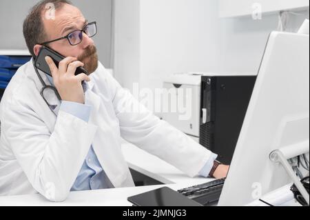 Medico in ufficio che parla al telefono Foto Stock