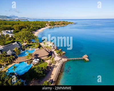 Splendido resort tropicale sulla spiaggia con piscina, lettini e palme durante una calda giornata di sole, paradiso de Foto Stock