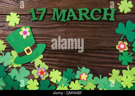 Felice San Patrizio's mockup di fiori fatti a mano cappello e shamrock Clover foglie su sfondo di legno. Foto Stock