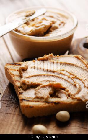 Panino con burro di arachidi e vista a basso angolo sul tagliere con i toast a parte. Concetto di alimentazione sana Foto Stock