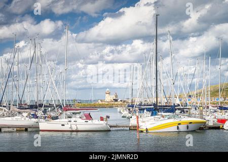 Faro di Howth visto attraverso alberi di barche a vela e yacht ormeggiati nel porto turistico di Howth Foto Stock