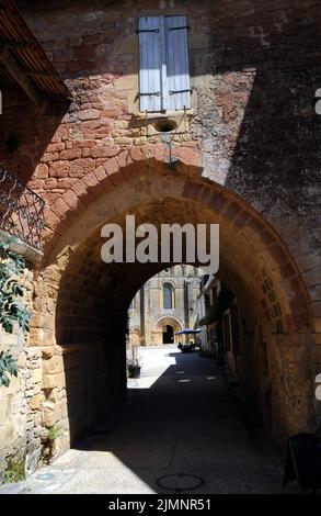 Un arco nel villaggio di Cadouin, Perigord Noir, conduce da una strada stretta attraverso la grande piazza del mercato e la bella chiesa abbaziale. Foto Stock