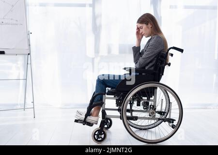 Full shot donna triste sedia a rotelle Foto Stock