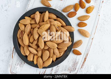 Piastra con vista dall'alto con mandorle in endocarpo, ciotola con drupe in conchiglia Foto Stock