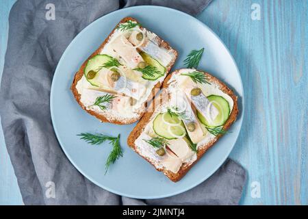 Aringa smorrebrod - tradizionali panini danesi. Pane di segale nero con aringa Foto Stock