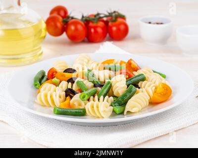 Insalata italiana con pomodori fusilli in pasta, olive, fagioli verdi, vista laterale, primo piano Foto Stock