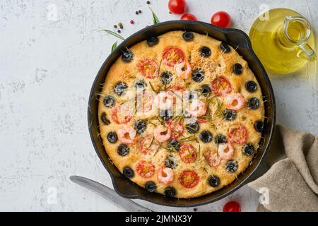 Focaccia, pizza di gamberi in padella, pane piatto italiano con pomodori, olive e rosmarino. Vista dall'alto, spazio copia, cemento bianco b Foto Stock