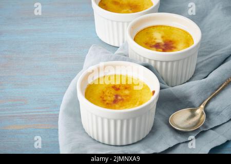 Crema catalana, dessert spagnolo in tre ramekin su tavolo blu, spazio copia Foto Stock