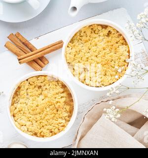 Apple crumble con striusel su tavolo grigio chiaro. Colazione con fiori. Foto Stock