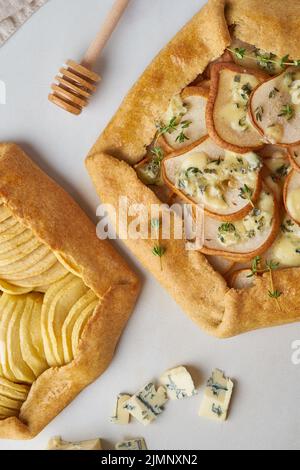 Galette di frutta, torta di mele con miele, torta di pere e formaggi salati, tavolo in marmo, verticale, vista dall'alto Foto Stock