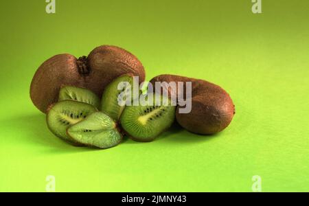 Kiwi organico brutto vegetale su sfondo verde. Orientamento orizzontale. Foto Stock