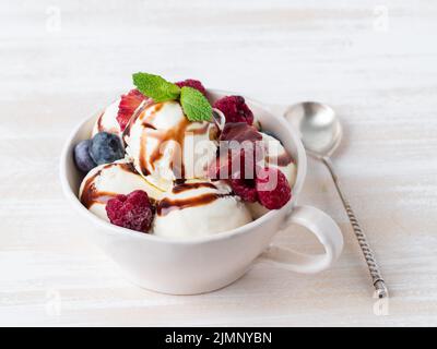 Palle di gelato alla vaniglia in tazza con lampone e mirtilli Foto Stock