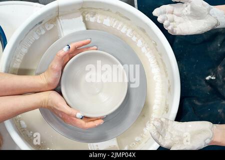 Donna che fa ceramica ceramica su ruota, mani primo piano. Concetto per donna in freelance Foto Stock