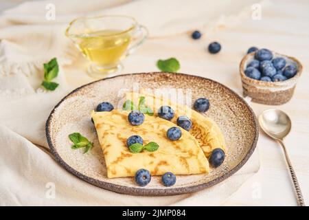 Due pancake con mirtilli e menta sul piatto, vista laterale Foto Stock