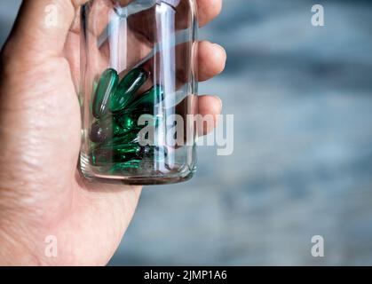 Close up vitamine verdi o integratori nel piccolo flacone di vetro trasparente fiale in mano della persona con spazio copia. Flaconcini di tenuta con capsule di pillole di farmaco Foto Stock