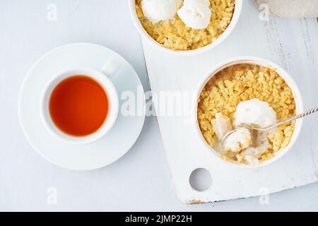 Crumble di mele con gelato, streusel. Colazione mattutina con tè su un tavolo grigio chiaro Foto Stock