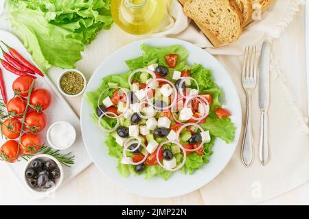 Insalata greca su piatto bianco su vecchio rustico tavolo di legno bianco, insalata fresca Foto Stock