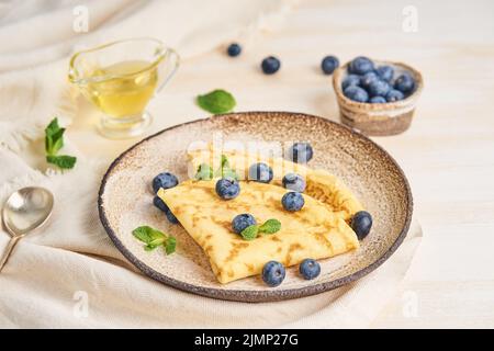 Due pancake con mirtilli e menta sul piatto, vista laterale Foto Stock