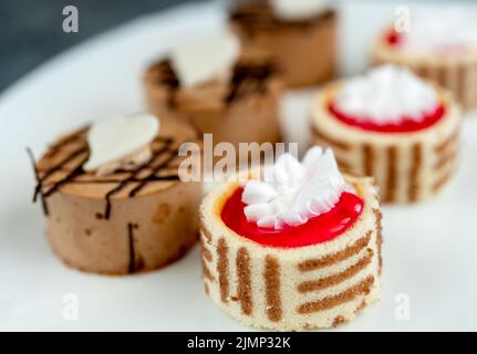 La piccola pasticceria con ripieno di differenti sulla piastra bianca Foto Stock