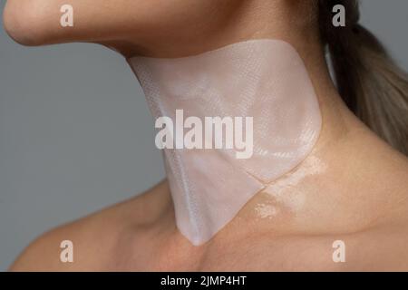 Donna con una maschera di protezione applicata sul collo Foto Stock