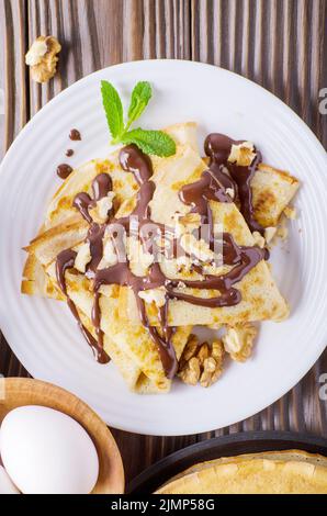 Piatto francese laici crepes con salsa di cioccolato noci uova e farina di legno sul tavolo da cucina Foto Stock