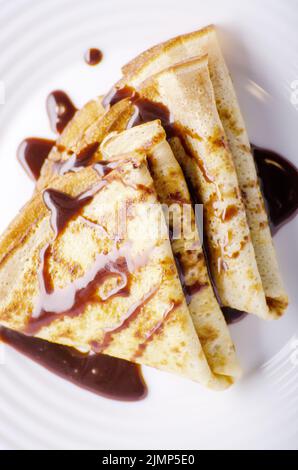 Piatto francese laici crepes con salsa di cioccolato nel piatto di ceramica su legno tavolo da cucina Foto Stock