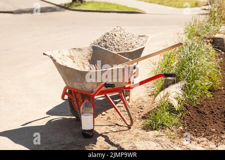 Carriola con ghiaia in cantiere. Foto Stock