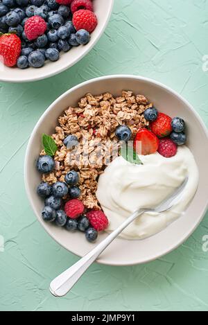 Un piatto di granola secca servito con frutta fresca alla bacche e yogurt. Piastra di farina d'avena. Cibo sano, dieta. Vista dall'alto. Foto Stock