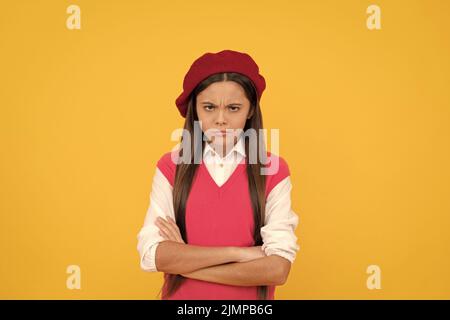 ragazza della scuola teen infelice in beretto francese su sfondo giallo, serietà Foto Stock