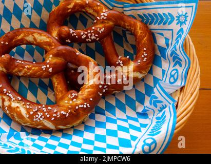 Deliziosa Brezeln bavarese o pretzel con crosta salata marrone su un tradizionale tovagliolo bavarese in un cestino Foto Stock