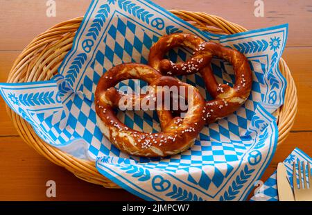 Deliziosa Brezeln bavarese o pretzel con crosta salata marrone su un tradizionale tovagliolo bavarese in un cestino Foto Stock