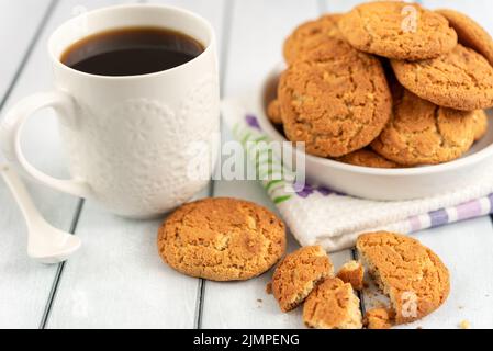 Accogliente vita di mattina con caffè e una tazza di biscotti di farina d'avena su un tavolo di legno. Foto Stock