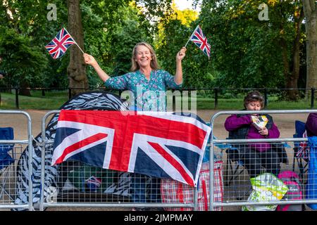 A British Woman Waves Union Flags Before the Queen's Birthday Parade, The Mall, Londra, Regno Unito. Foto Stock