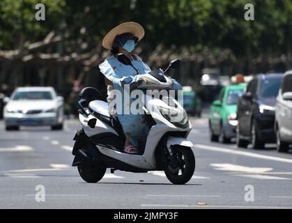 Fuyang, Cina. 07th ago 2022. Una donna guida una moto scooter mentre indossa un cappello con un enorme brim durante il tempo caldo. Secondo le previsioni dell'Osservatorio Meteorologico Centrale della Cina, nei prossimi 10 giorni, le alte temperature continueranno in alcune parti della Cina, con la temperatura massima che raggiunge i 37-39 ° C e la temperatura locale di 40 ° C o superiore. Credit: SOPA Images Limited/Alamy Live News Foto Stock