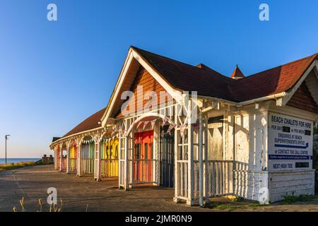 Una terrazza di colorate capanne storiche Edwardiane o chalet sulla South Bay a Scarborough, North Yorkshire, Inghilterra. Ora derelitto a causa dello slittamento della terra. Foto Stock