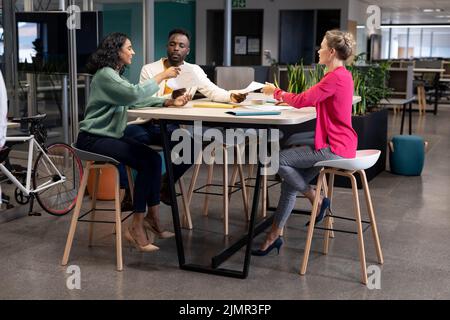 Colleghi aziendali multirazziali che discutono di documenti durante l'incontro nel luogo di lavoro moderno Foto Stock