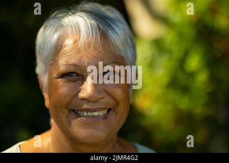 Primo piano ritratto di sorridente donna anziana biraciale con corti capelli grigi nel parco Foto Stock