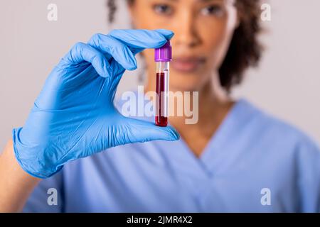 Ritratto di medico di metà adulta afroamericana indossando un guanto che tiene la provetta con sangue Foto Stock
