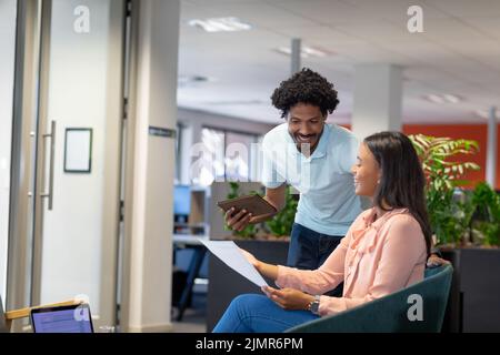 Sorridenti professionisti multirazziali che parlano di documenti al posto di lavoro moderno Foto Stock