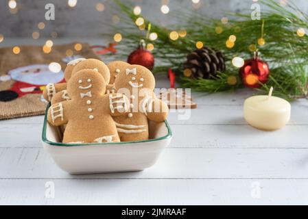 Carta di Natale con biscotti Gingerbread uomo, decorazioni di festa su uno sfondo di legno. Foto Stock