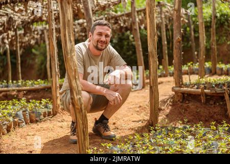 Uomo felice in visita piantagione di caffè, piantine, alberi da in Sud Africa Foto Stock