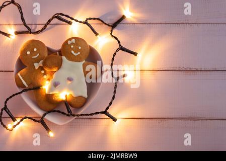 Biscotti di pan di zenzero in una ciotola a forma di cuore su uno sfondo di legno. Foto Stock