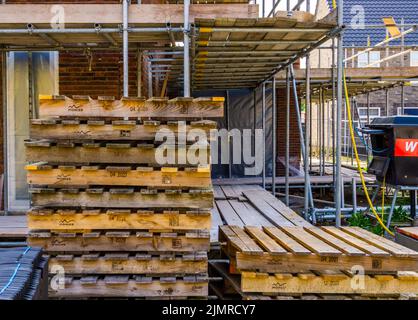 Pallet vuoti con impalcatura sullo sfondo, cantiere a Rucphen, Paesi Bassi, 6 maggio 2022 Foto Stock