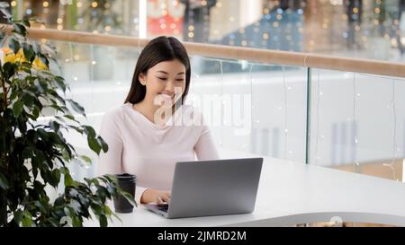 Ragazza asiatica femmina studente che riceve e-mail risultato di esami prova avviso di occupazione messaggio dal ragazzo in social network online guardando il laptop Foto Stock