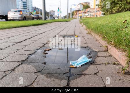 Pandemia a Kaliningrad, Russia. Una maschera blu perduta si trova sul terreno di Moskovsky Prospekt a Kaliningrad. Foto Stock