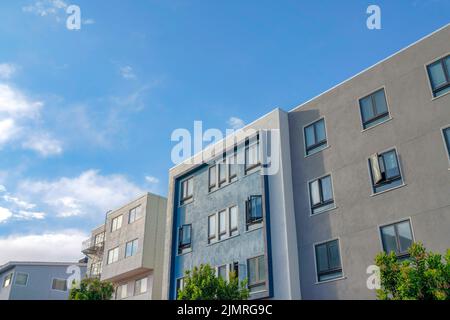 Moderni edifici di appartamenti con esterni grigi, blu e bianchi a San Francisco, California. C'è un edificio di appartamenti sulla sinistra con emergenza Foto Stock