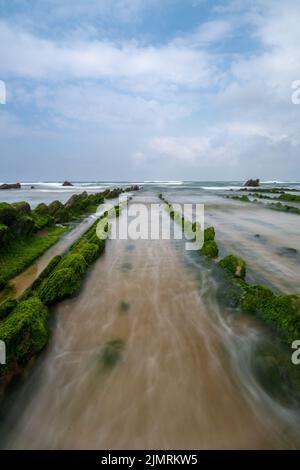 Vista a lunga esposizione delle formazioni rocciose di Flysch con la bassa marea sulla spiaggia di Barrika vicino a Bilbao Foto Stock