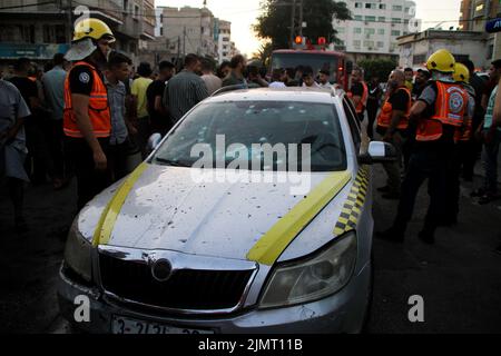 Città di Gaza, striscia di Gaza, Palestina. 7th ago 2022. Gaza, Palestina. 07 agosto 2022. I membri della Difesa civile Palestinese ispezionano un'automobile colpita ad un bivio a Gaza City da aerei da guerra israeliani. Tre palestinesi sono morti a seguito dell'attacco, mentre l'offensiva israeliana continua nella striscia di Gaza per un terzo giorno. Le vittime palestinesi hanno continuato ad aumentare a causa delle continue incursioni aeree israeliane, con almeno 35 palestinesi uccisi e oltre 250 feriti nella striscia di Gaza. La Jihad islamica ha sparato centinaia di razzi in Israele in rappresaglia all'offensiva militare israeliana e al Foto Stock