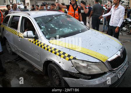 Città di Gaza, striscia di Gaza, Palestina. 7th ago 2022. Gaza, Palestina. 07 agosto 2022. I membri della Difesa civile Palestinese ispezionano un'automobile colpita ad un bivio a Gaza City da aerei da guerra israeliani. Tre palestinesi sono morti a seguito dell'attacco, mentre l'offensiva israeliana continua nella striscia di Gaza per un terzo giorno. Le vittime palestinesi hanno continuato ad aumentare a causa delle continue incursioni aeree israeliane, con almeno 35 palestinesi uccisi e oltre 250 feriti nella striscia di Gaza. La Jihad islamica ha sparato centinaia di razzi in Israele in rappresaglia all'offensiva militare israeliana e al Foto Stock